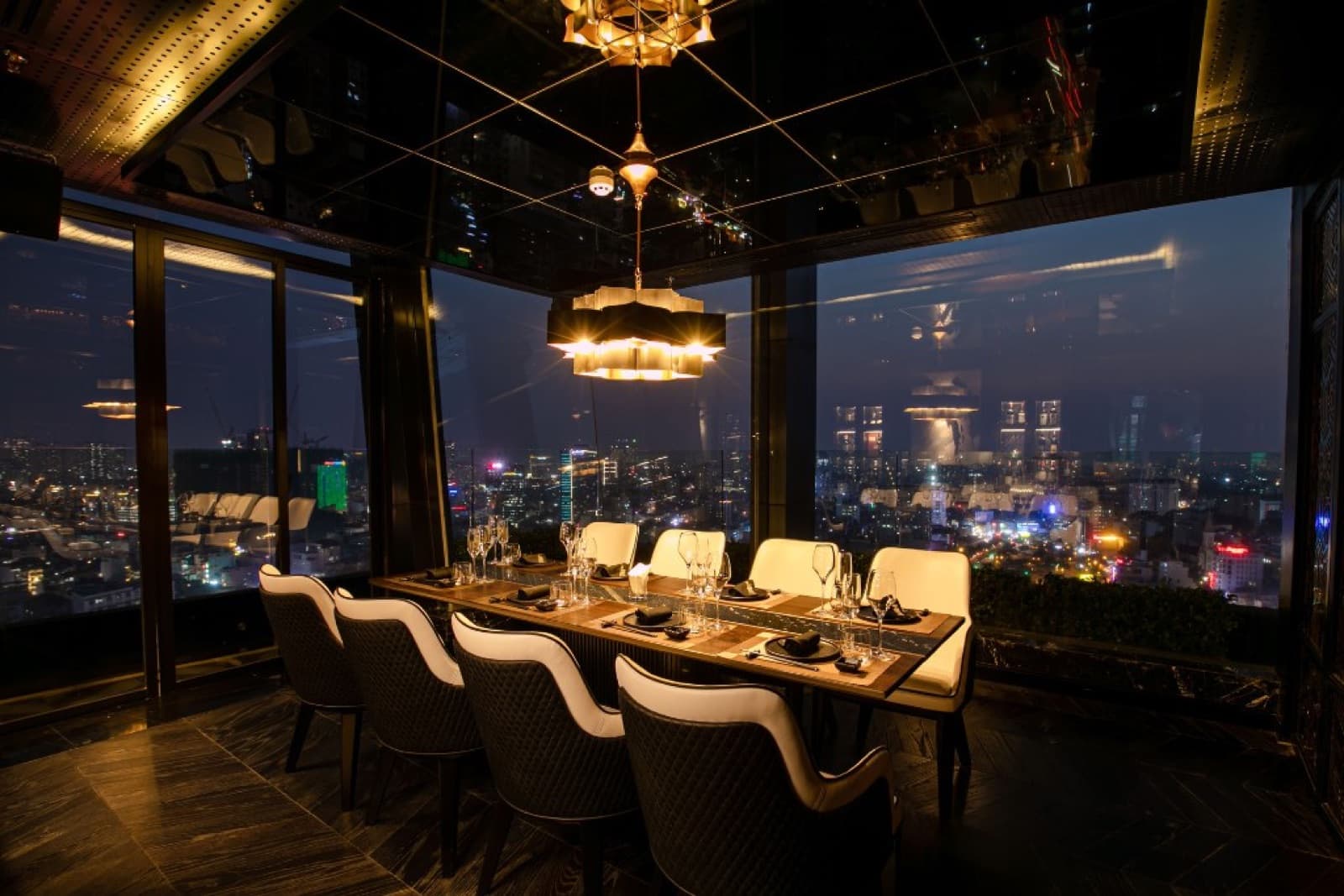 Chill Dining laid as a long table at night, unoccupied, against the floor-to-ceiling city view.