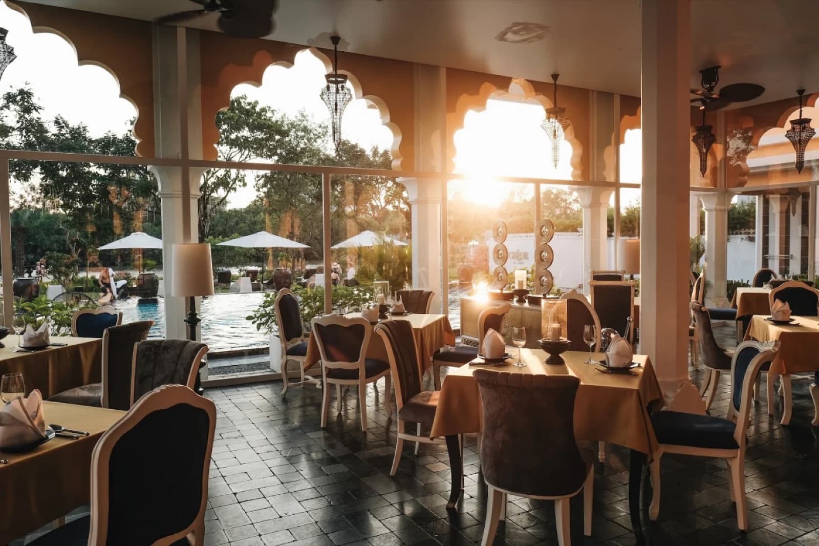 Covered glass-walled dining pavilion at Riverview Dining with tables set overlooking the pool