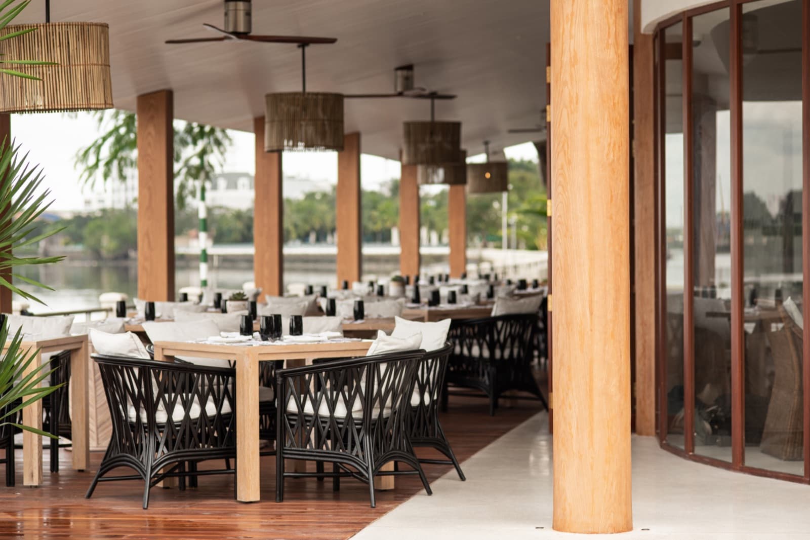Coastal Saigon covered riverside terrace set with dining tables and a view over the Saigon River