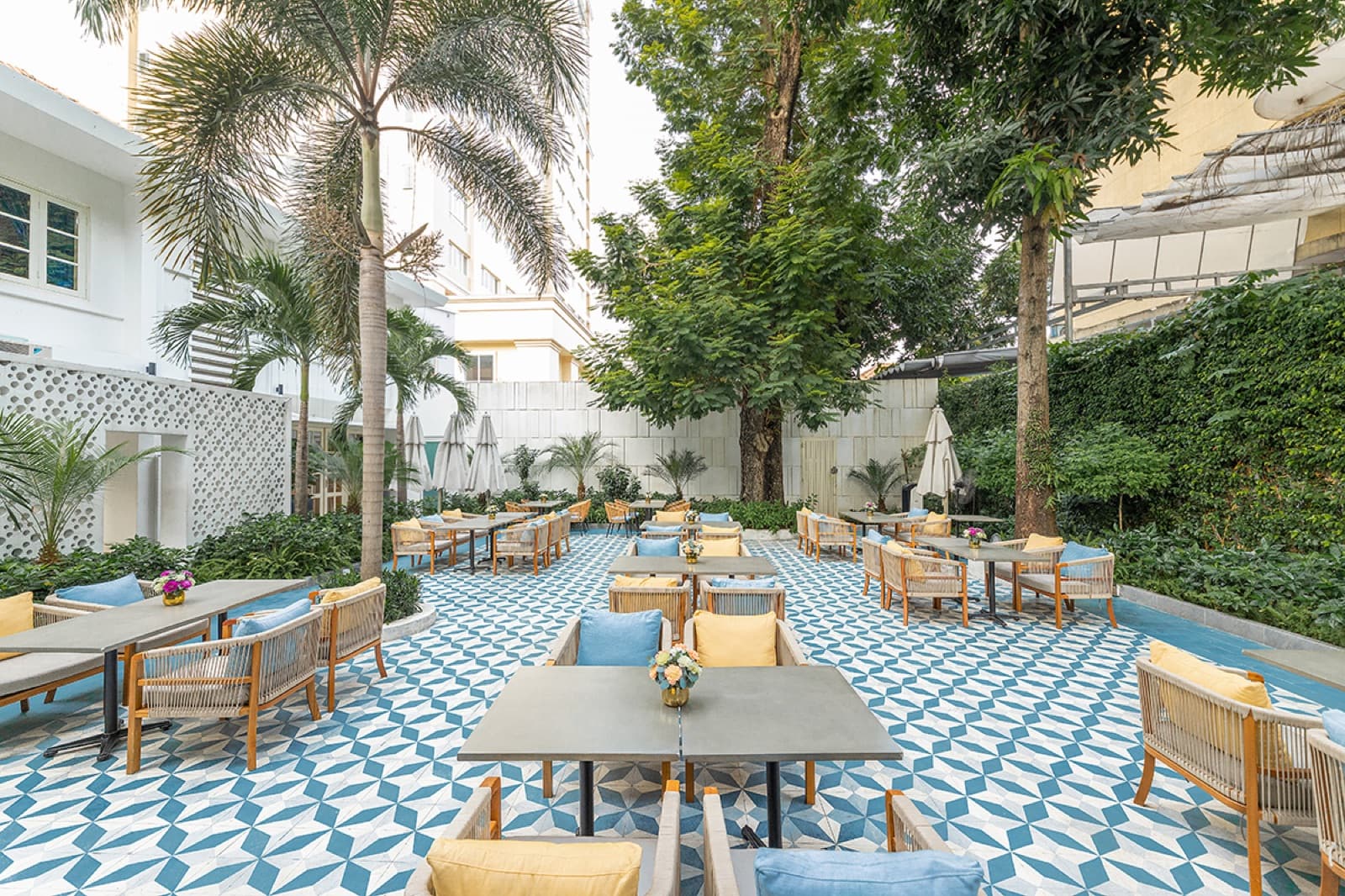 Côn Sơn Garden Area outdoor courtyard with blue-and-white tiled floor, palm trees and rattan lounge seating