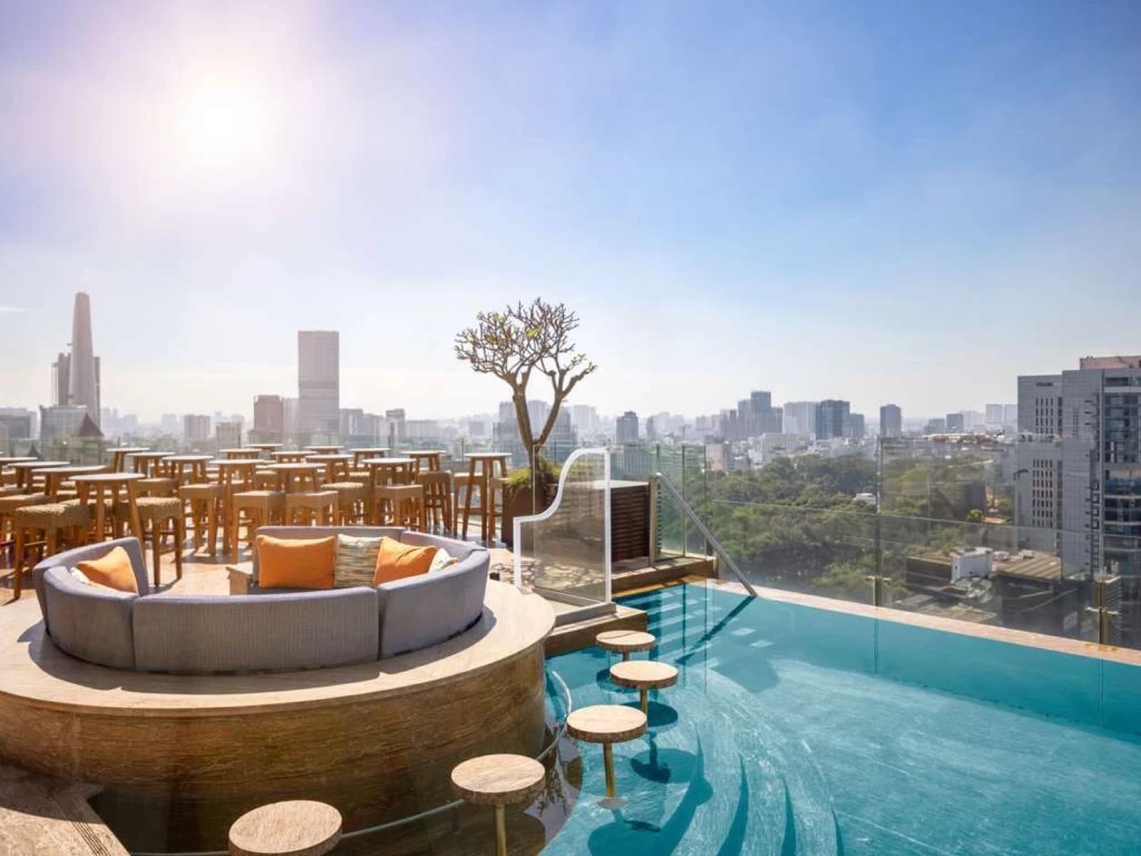 Social Club rooftop infinity pool and lounge seating at Hôtel des Arts Saigon by day, city skyline behind