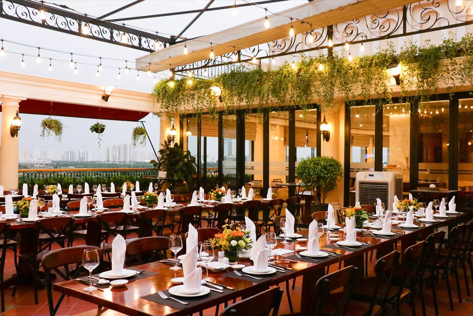 Breeze Sky Bar rooftop terrace at Hotel Majestic Saigon set with dining tables under string lights and greenery