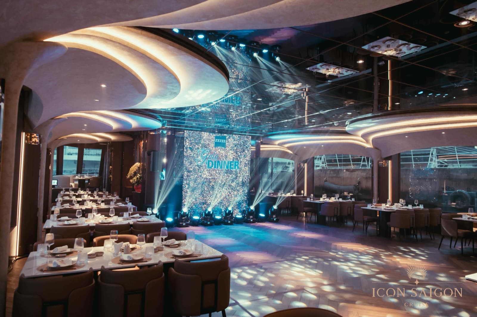 ICON Dining hall dressed for a gala dinner aboard ICON Saigon, with an LED stage backdrop and river-view windows