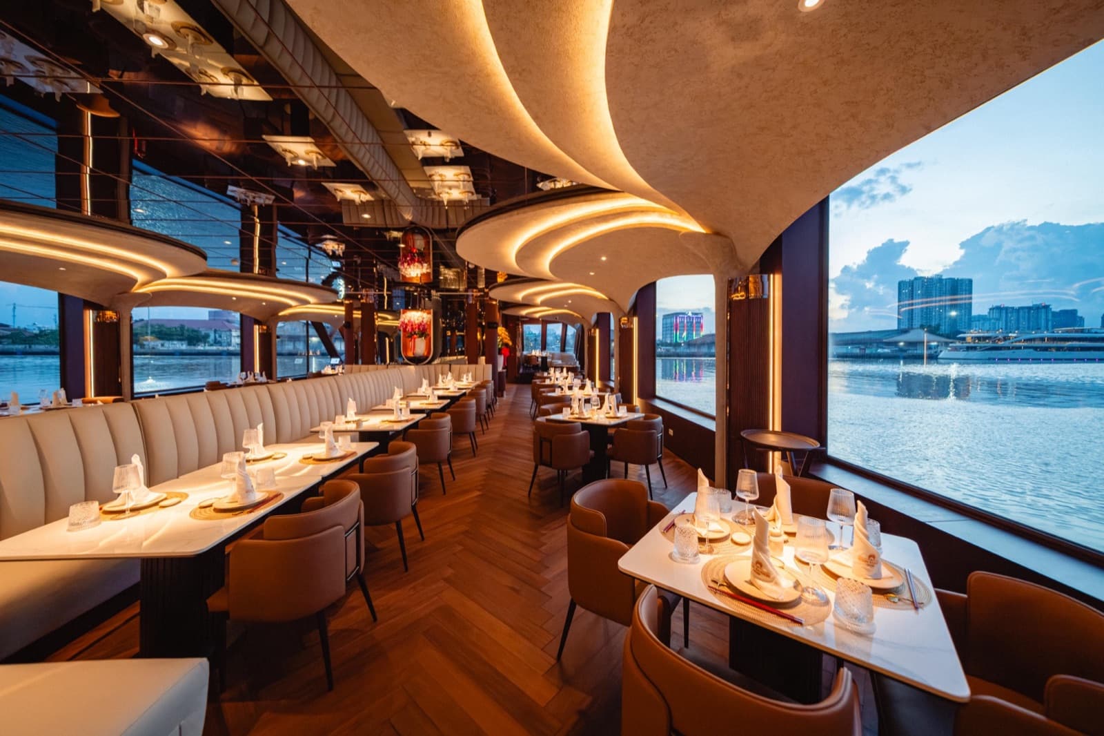 Skydeck VIP Room aboard ICON Saigon set for dining with river-view windows at dusk