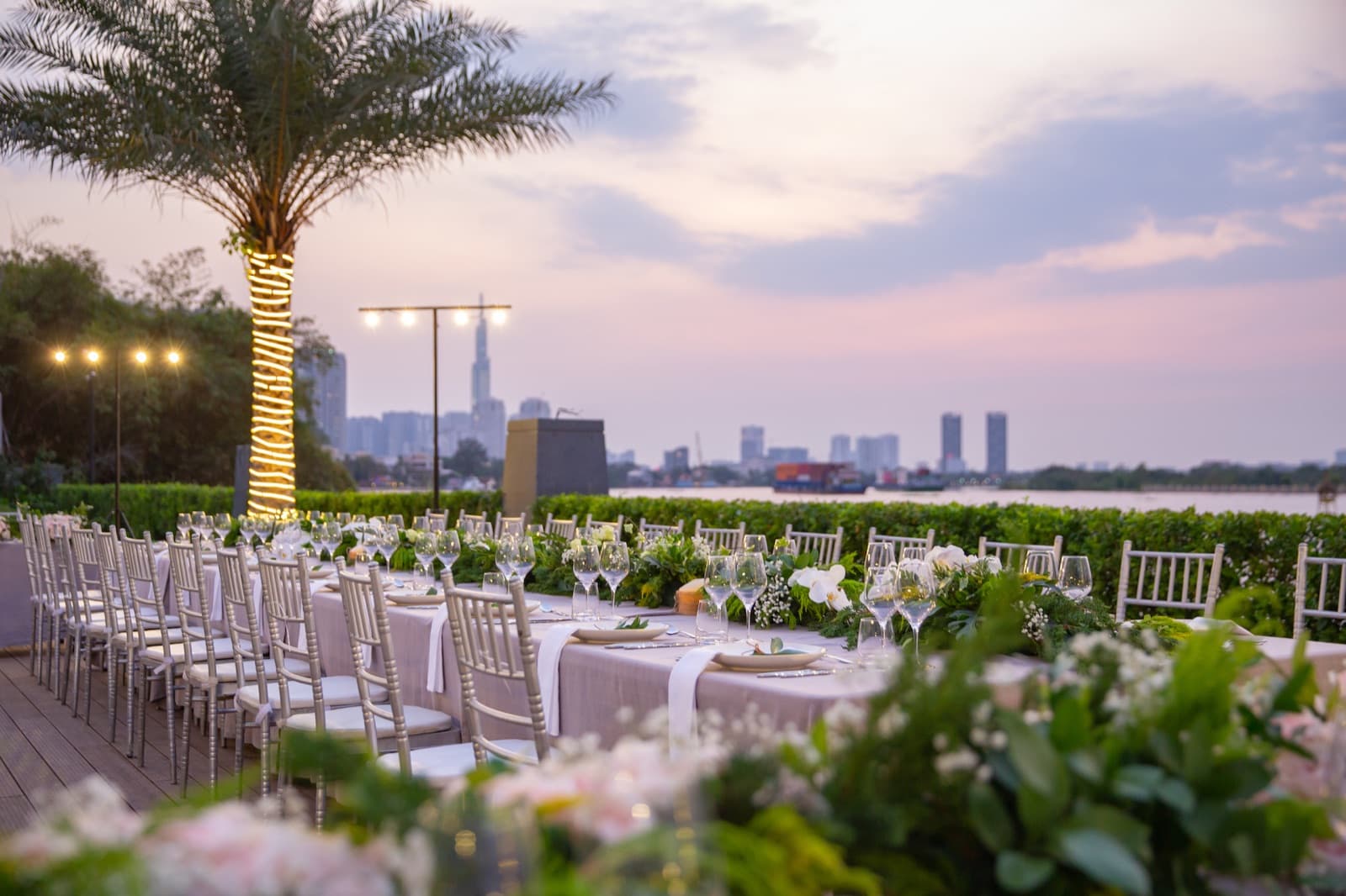 The Pool Deck at Mia Saigon laid for a banquet at sunset, unoccupied, looking across the river to the city.