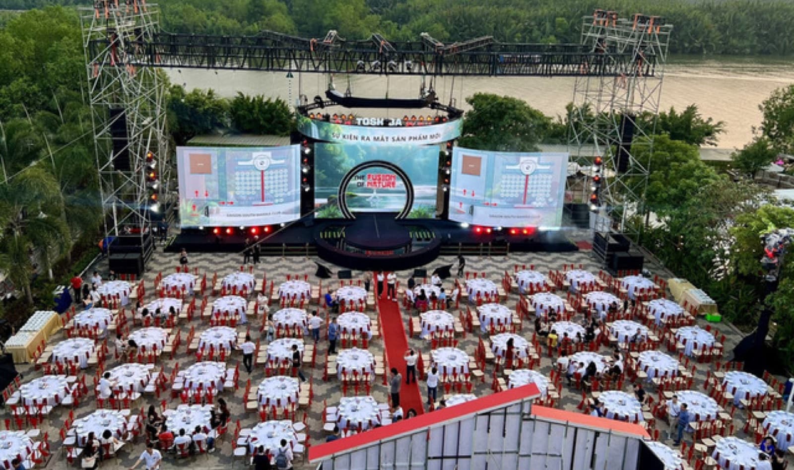 Marina Bay outdoor event with stage, screens and banquet seating beside the river