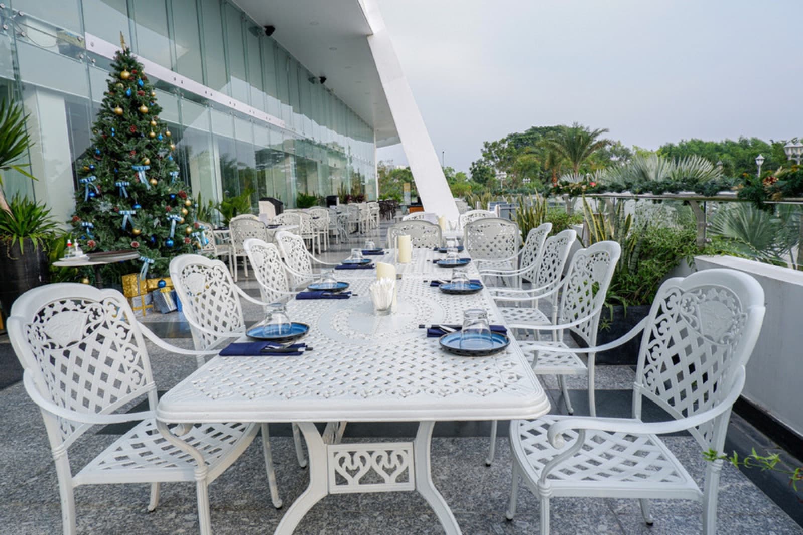 Terrace outdoor dining setup with white tables and riverfront greenery