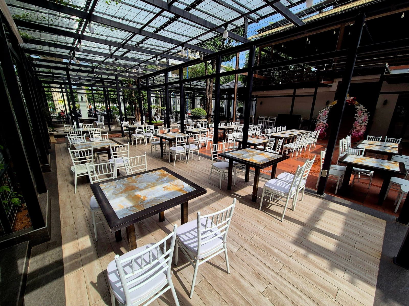 Covered outdoor courtyard with wood-topped tables and white chairs