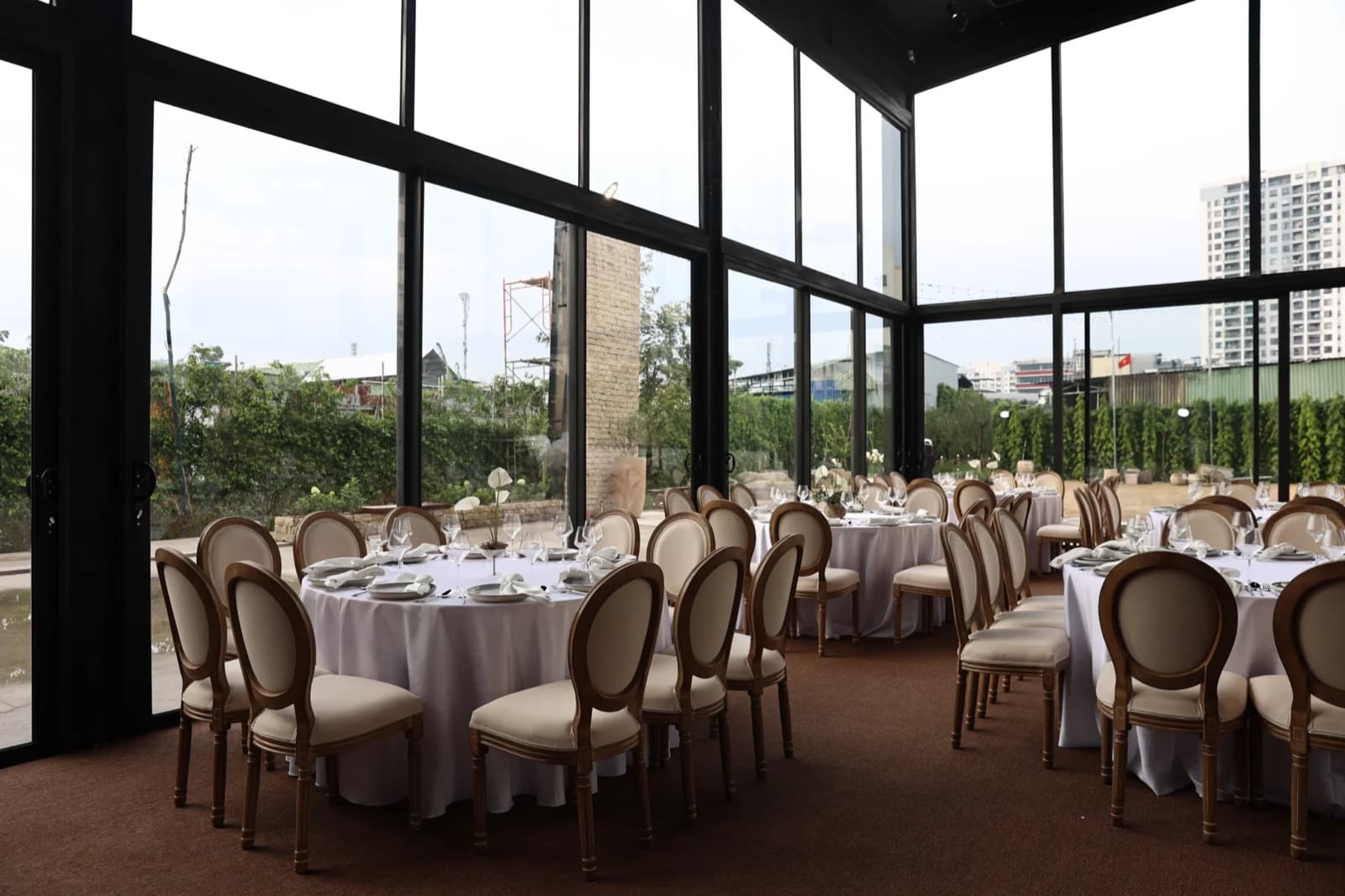 The Harvest Saigon glass event hall arranged with round dining tables and chairs