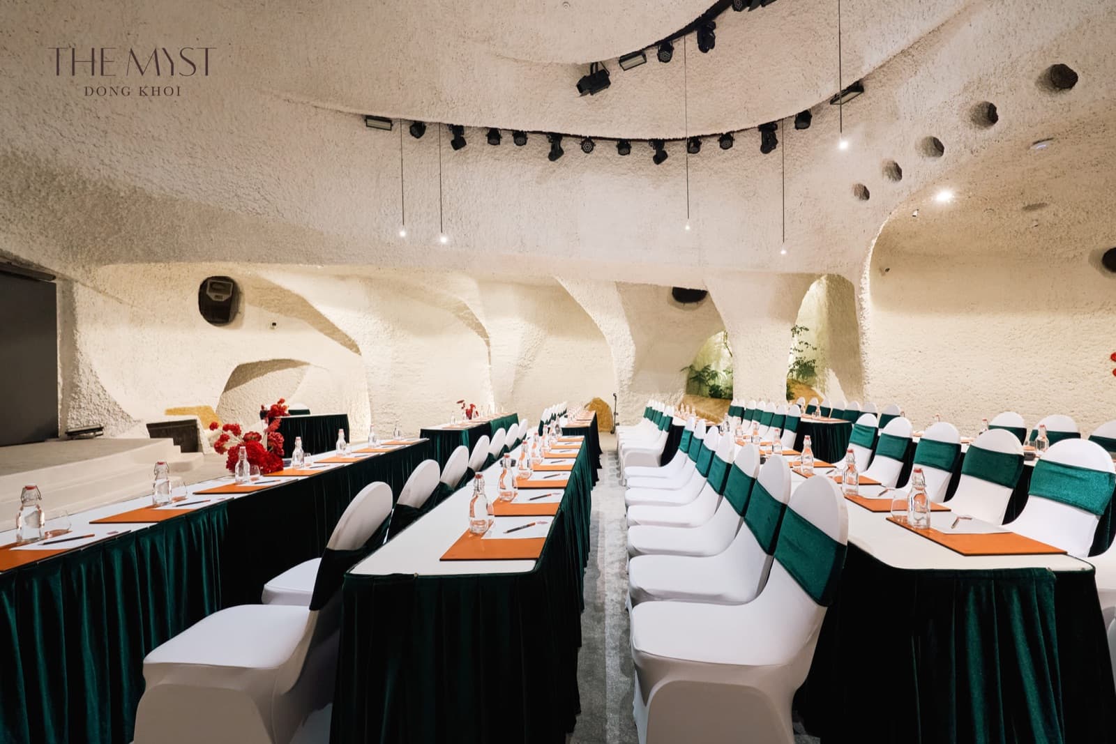 The Myst Đồng Khởi's ballroom in classroom layout against its sculpted white walls, unoccupied.