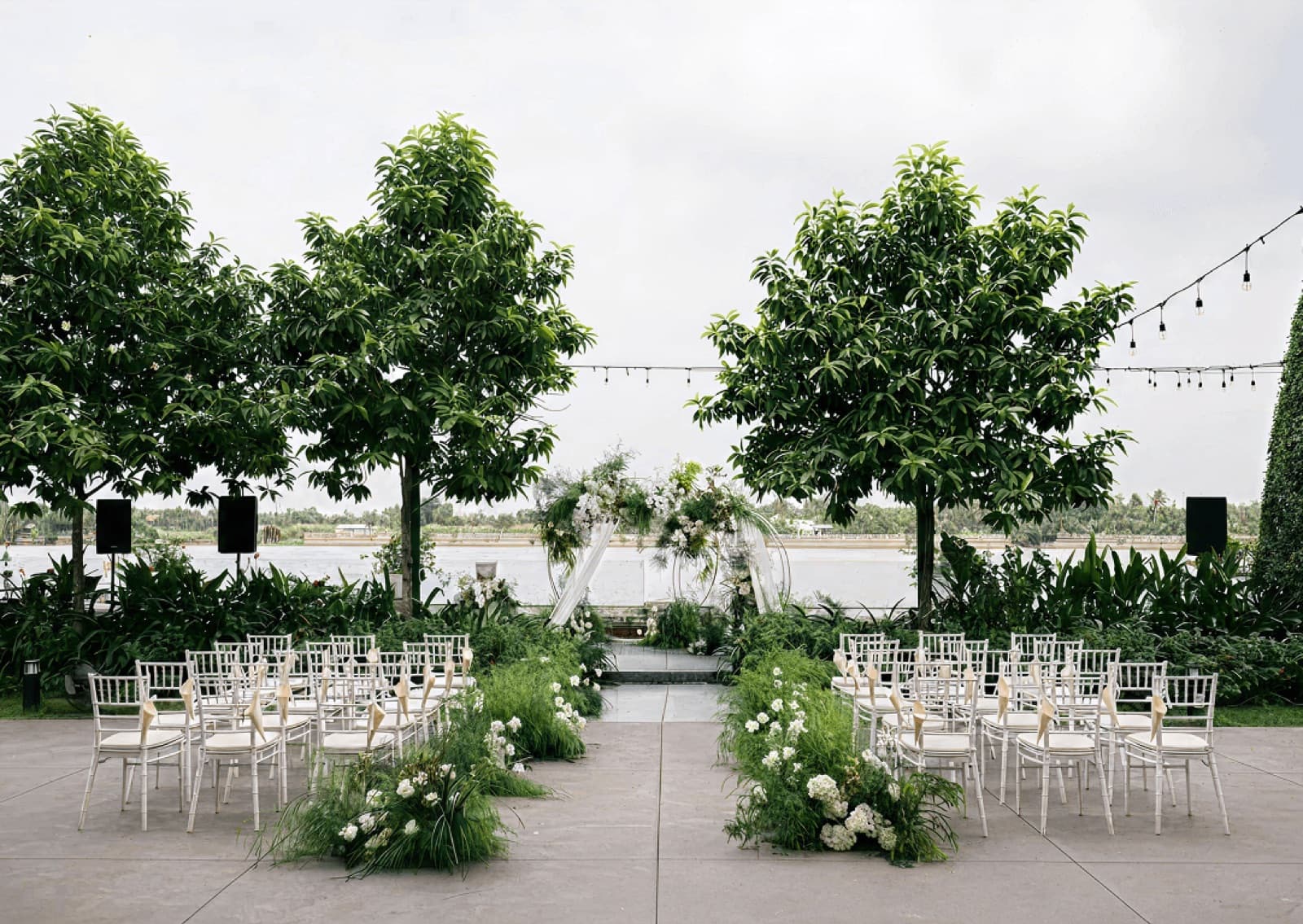 A ceremony set up on The Veranda's garden lawn at Villa Sông Saigon, under the trees by the river.